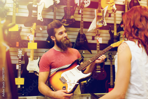 assistant showing customer guitar at music store