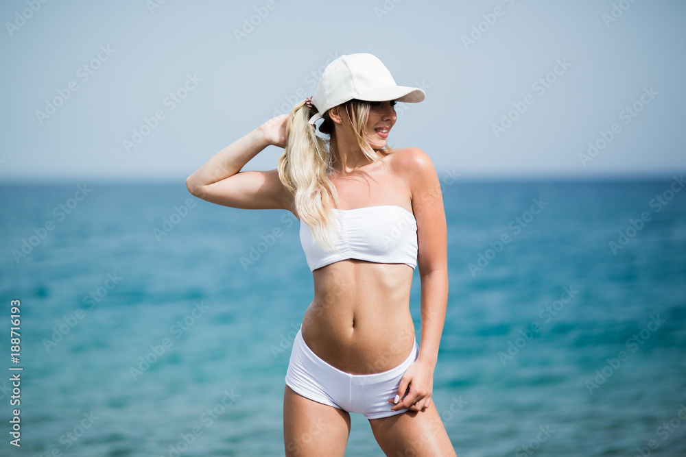 Fitness girl with a perfect body is smiling near the sea Fitness girl with a perfect body is smiling near the sea