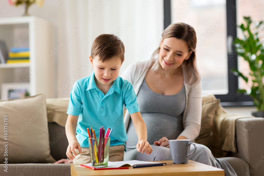 pregnant mother and son with workbook at home
