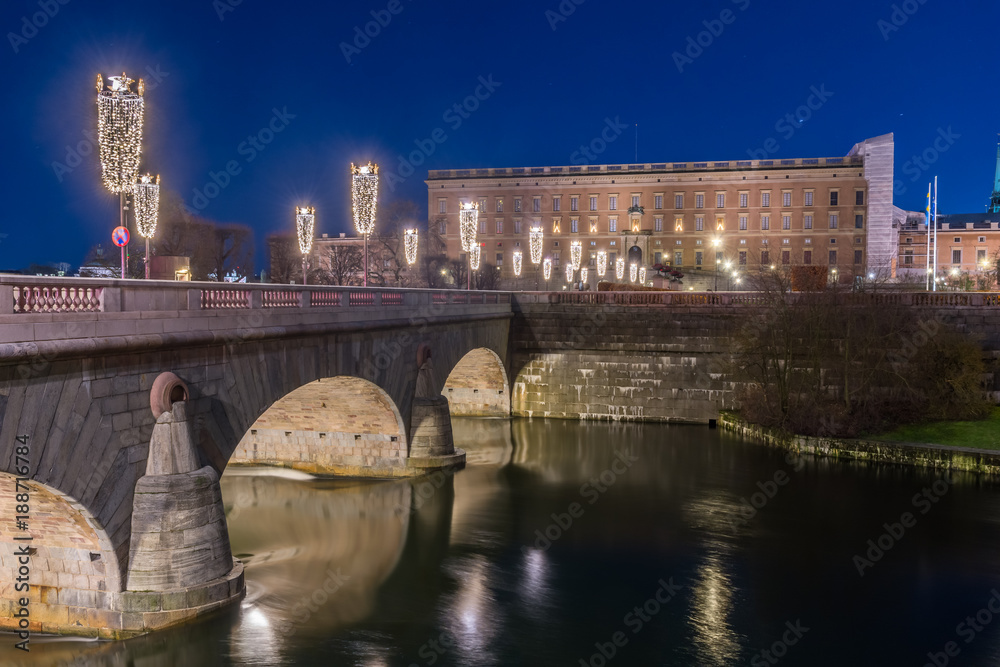 Strömbron vackert upplyst av julbelysning som leder till Stockholm slott