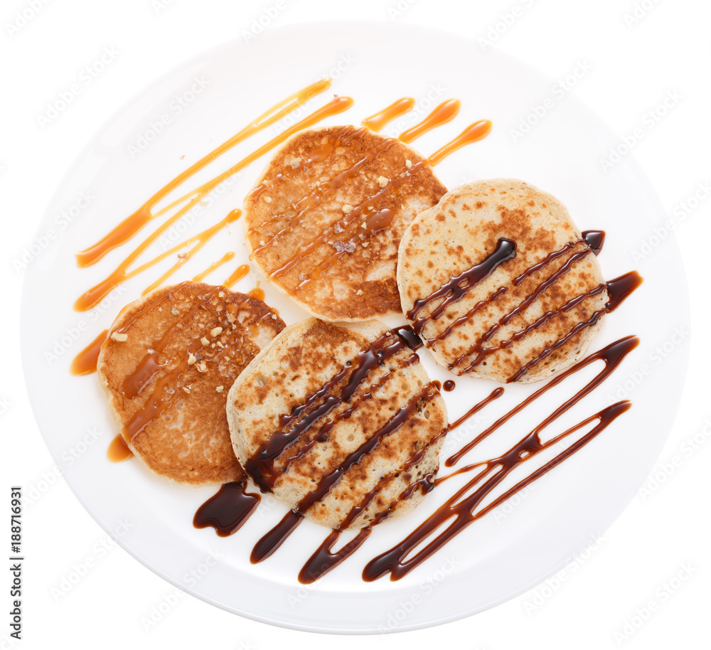 Serving pancakes with chocolate syrup and caramel syrup. Isolated on white background. Top view. Serving pancakes with chocolate syrup and caramel syrup. Isolated on white background. Top view.