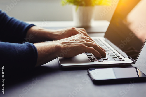 Man typing on laptop in the office, toned image