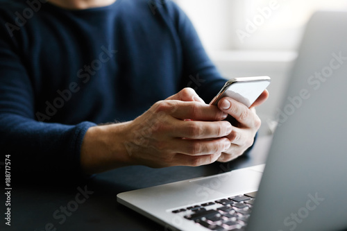 Man with mobile phone and laptop in office