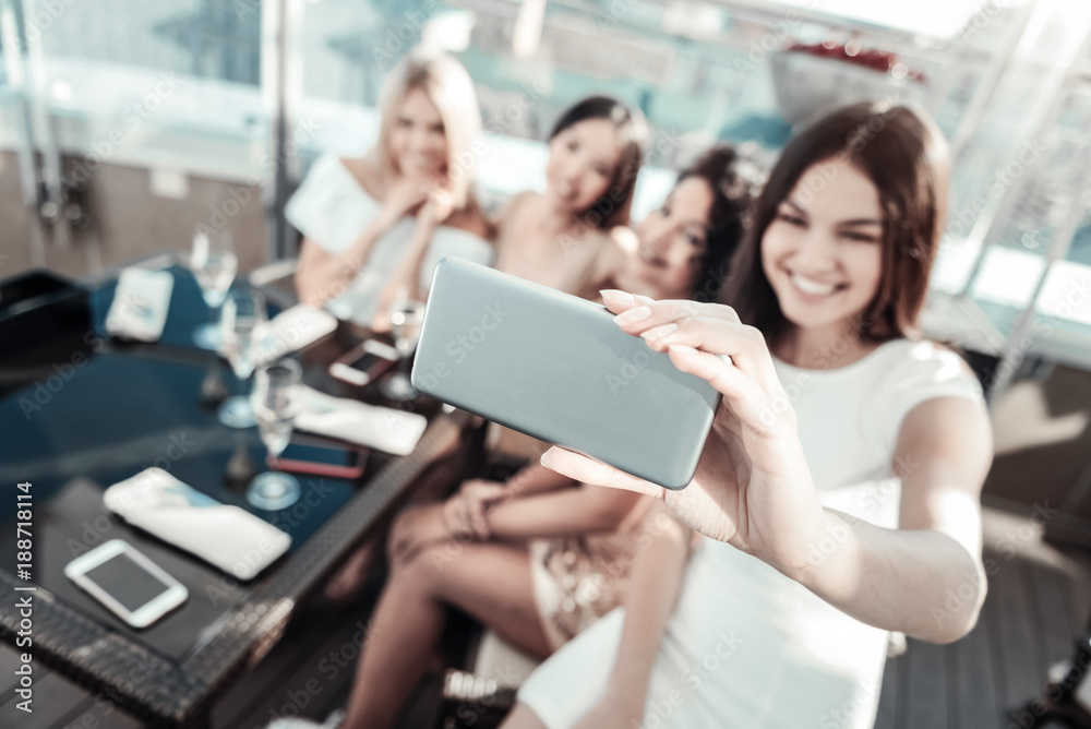 Best gadgets. Happy young girls sitting by the table on the rooftop restaurant making photo and spending time together. Best gadgets. Happy young girls sitting by the table on the rooftop restaurant making photo and spending time together.