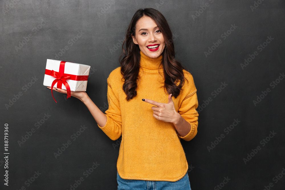 Smiling woman in sweater holding gift box on the palm Smiling woman in sweater holding gift box on the palm