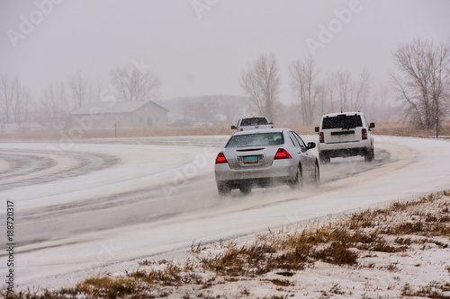 Vehicles traveling on slippery icy road in snowstorm.