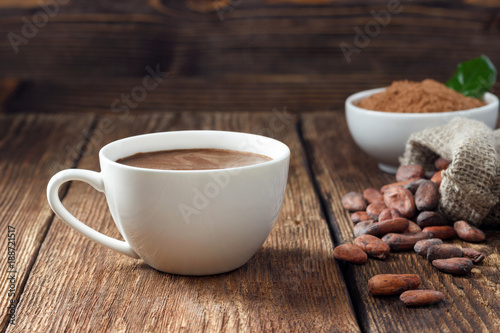 Canvas-taulu Cocoa drink in white mug, cocoa powder and cocoa beans on wooden table
