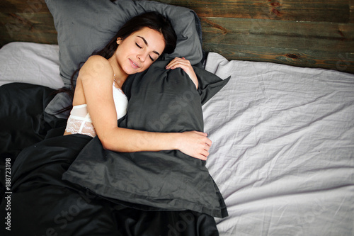 Side view of beautiful young woman smiling while sleeping in her bed at home