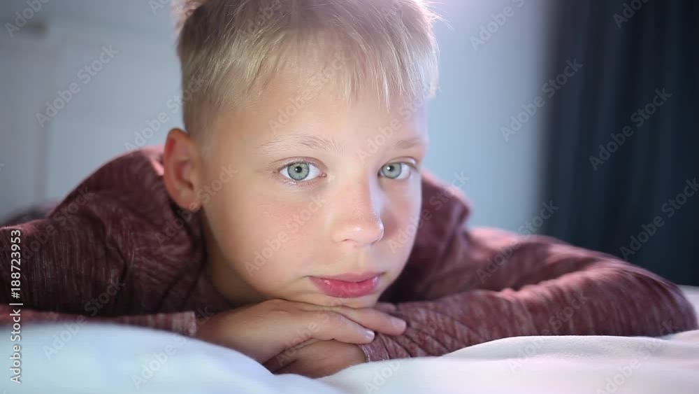 Closeup portrait of thoughtful boy laying in bed. White cute kid looks at camera. Closeup portrait of thoughtful boy laying in bed. White cute kid looks at camera.