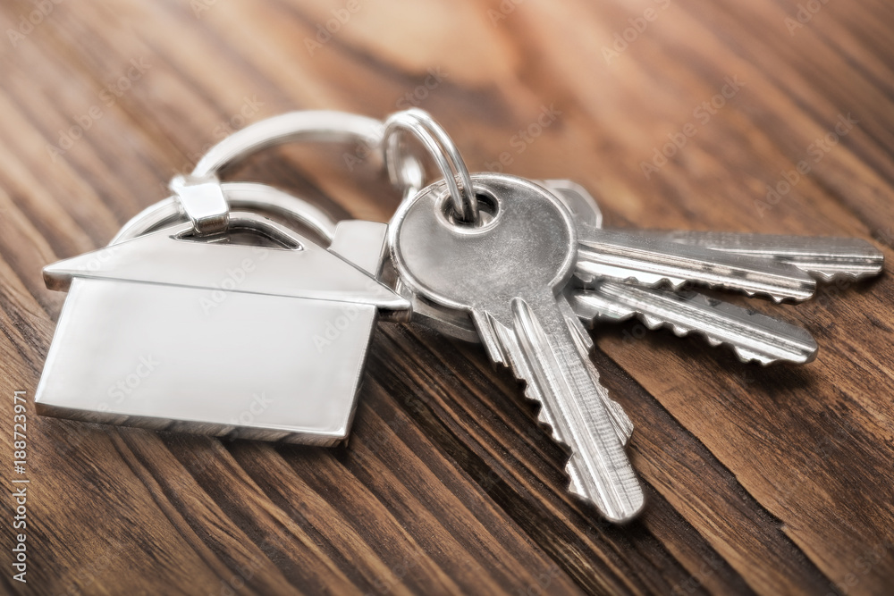 estate concept, keychain with house symbol, key on wooden background estate concept, keychain with house symbol, key on wooden background
