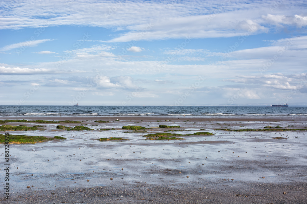 Coastal landscape in Scotland, UK, the town of Kirkcaldy. Low tide, ships on the horizon.