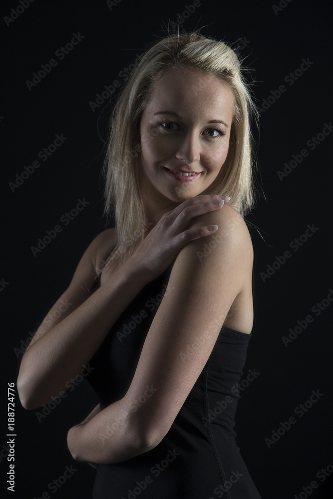Beautiful blond woman in black top in dark with selective lighting and hands in hair Beautiful blond woman in black top in dark with selective lighting and hands in hair