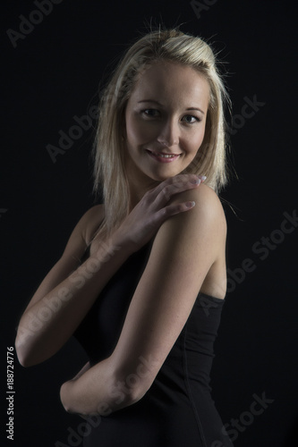 Beautiful blond woman in black top in dark with selective lighting and hands in hair