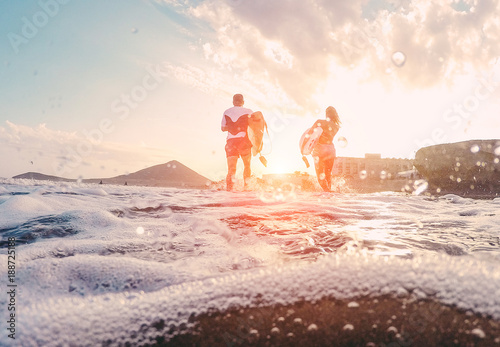 Photography Surfers couple running with surf boards on the beach