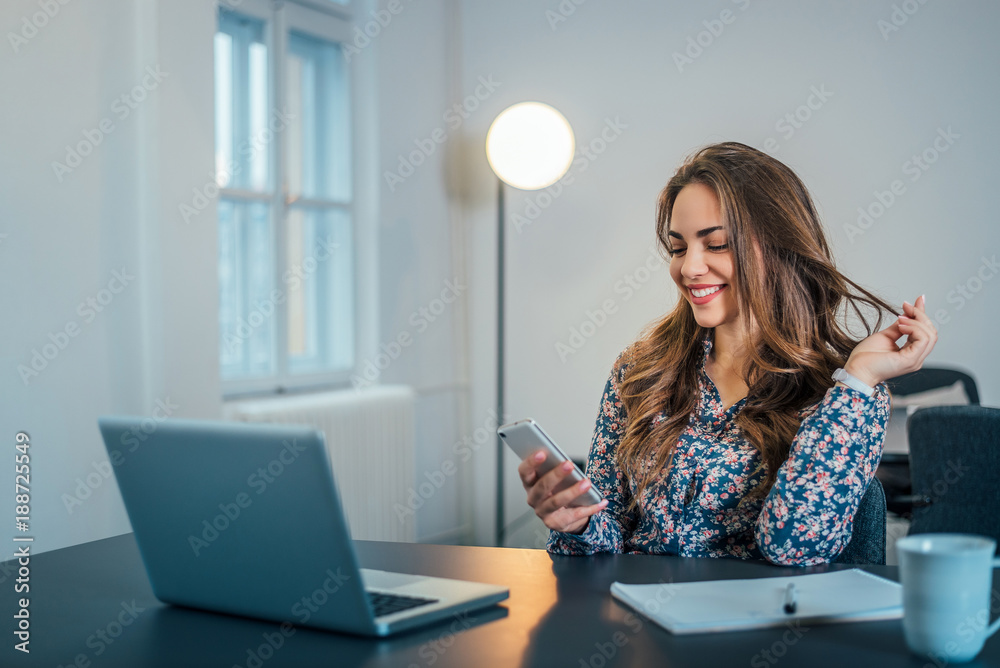 Gorgeous woman in office reading message on phone. Gorgeous woman in office reading message on phone.