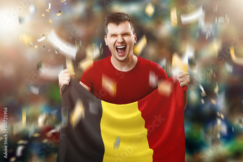 A Belgian fan, a fan of a man holding the national flag of Belgium in his hands. Soccer fan in the stadium. Mixed media