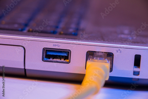 Closeup of Ethernet cable plug inserted into port on the side of a laptop