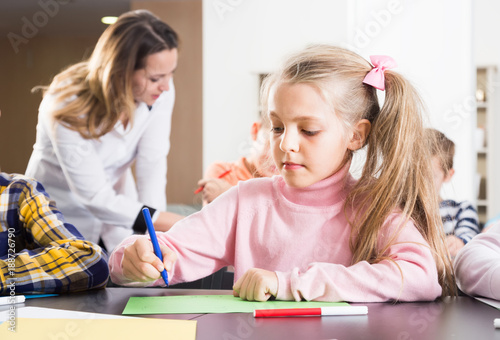 Female teacher and elementary age children drawing