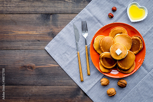 Pile of hot homemade pancakes on bright plate. Blue tablecloth, dark wooden background top view copy space photo