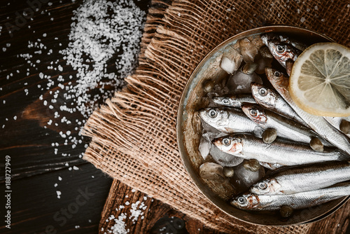 raw fresh fish on a silver platter with ice capers and lemon