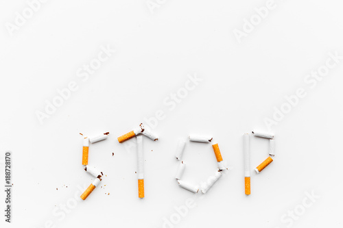 Stop smoking. Word stop lined cigarettes on white background top view copy space