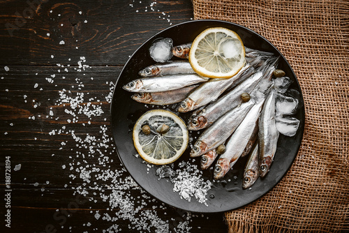 raw fresh fish on a plate with salt and lemon in a rustic style on a wooden surface photo