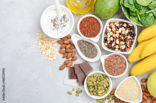 Healthy food nutrition dieting concept. Banana, chocolate, spinach, avocado, apple, quinoa, chia, flax seeds, yogurt, almond, beans, oat, pumpkin seeds, olive oil. Top view, flat lay, copy space.