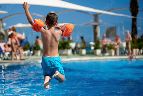 European boy having fun jumping into the pool.