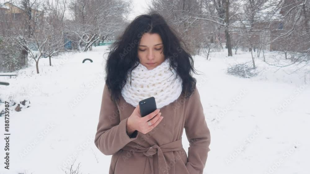 Young Caucasian Woman using a smartphone in winter snowy time. Young Caucasian Woman using a smartphone in winter snowy time.