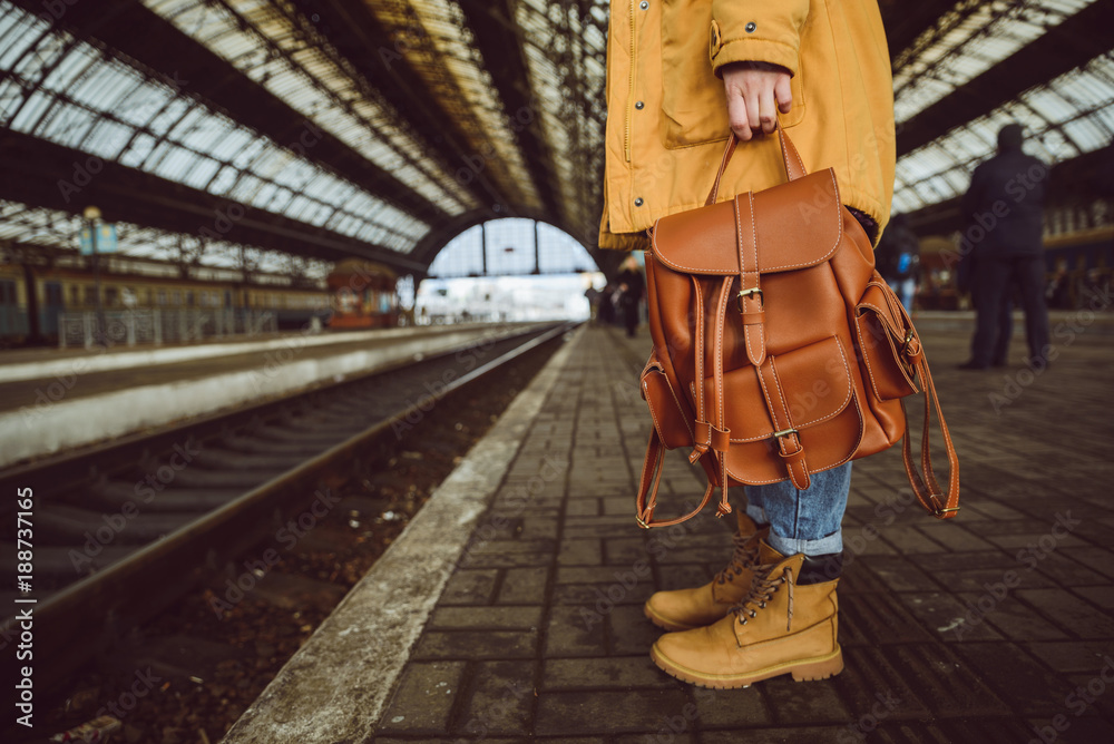 woman stand on the railway station hold backpack