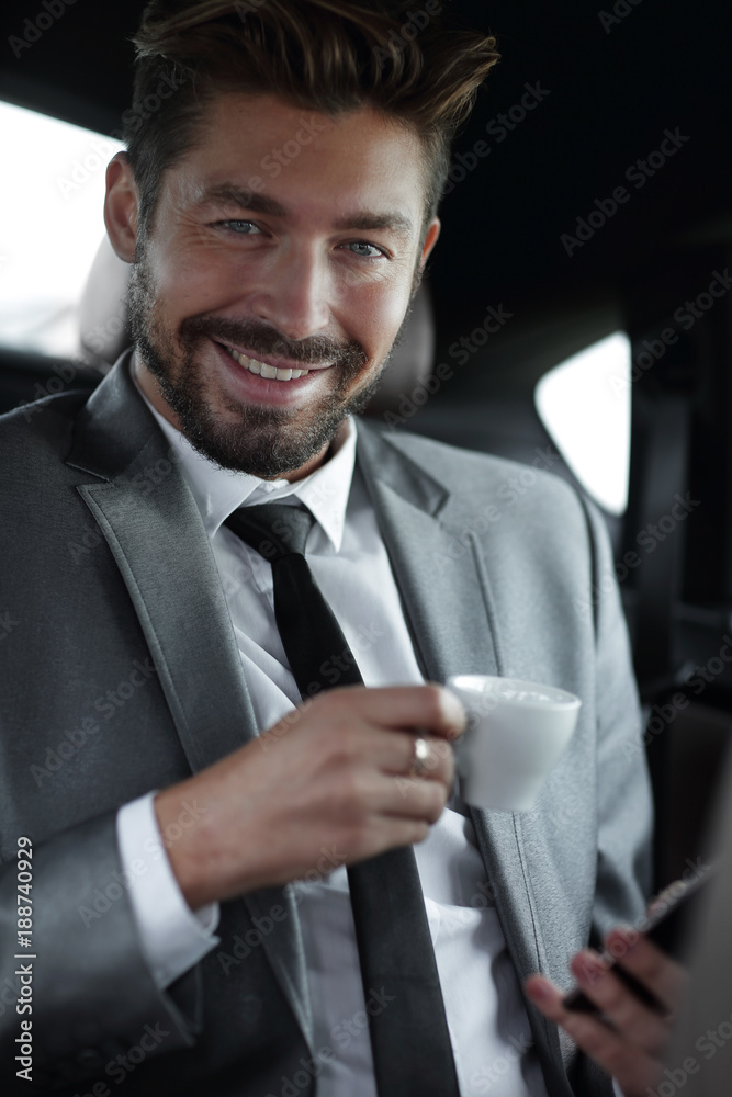 Businessman drinking coffee in the back seat of a car Businessman drinking coffee in the back seat of a car