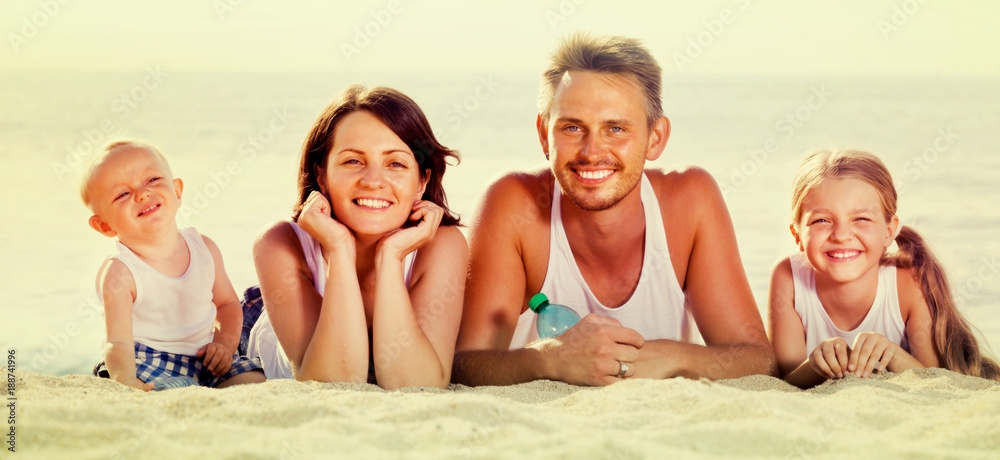 couple with two children lying on beach .