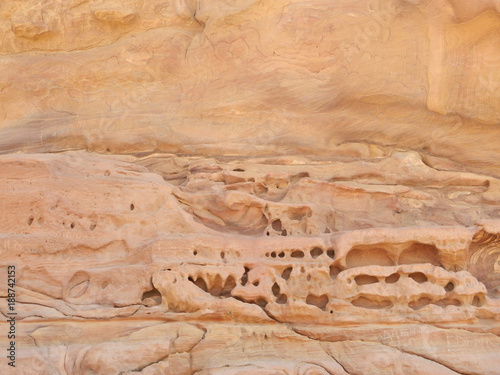 Weathered rose-red sandstone rock face with erosion holes in the ancient Nabataean City of Petra, Jordan