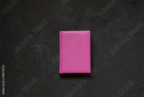 Lilac notepad on black concrete background. Top view.