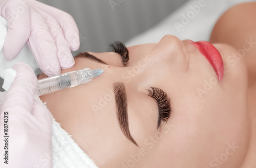 The doctor cosmetologist makes the Rejuvenating facial injections procedure for tightening and smoothing wrinkles on the face skin of a beautiful  young woman in a beauty salon.Cosmetology skin care.