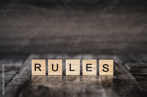 the word rules made of bright wood cubes with black letters on a dark wooden background