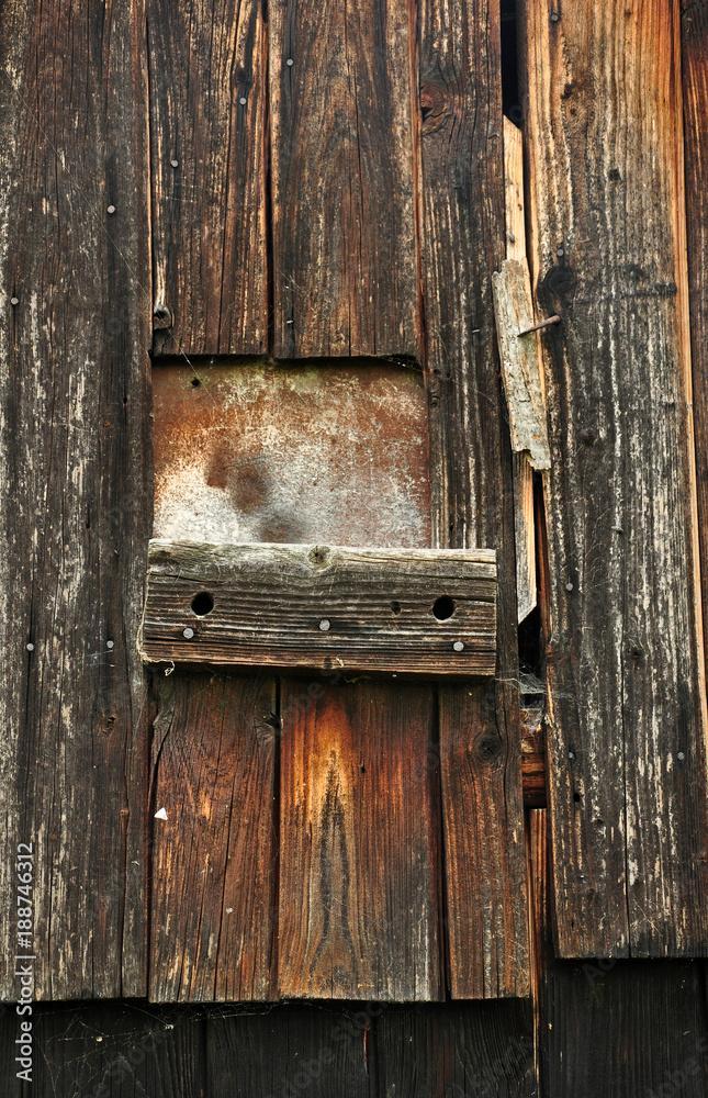 Old wooden closed door with a window with a rusty sheet