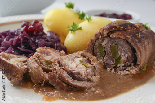 beef roulade with red cabbage, potatoes and sauce, german meat roll stuffed with cucumbers and bacon, close up