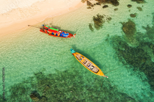 Drone flying under the amazing tropical bay with clear water, white beach and traditional longtail boats. 
Aerial view of beautiful bay and sea with clear turquoise water. Paradaise island, Thailand. photo