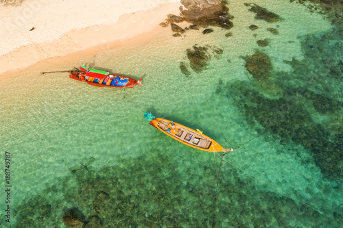 Drone flying under the amazing tropical bay with clear water, white beach and traditional longtail boats. 
Aerial view of beautiful bay and sea with clear turquoise water. Paradaise island, Thailand. photo