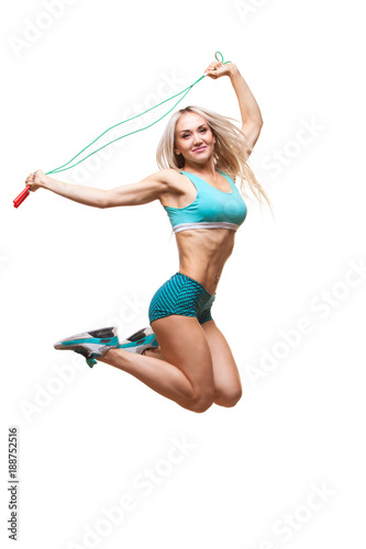 Full length image of a young sports woman jumping on skipping rope over white background © satyrenko