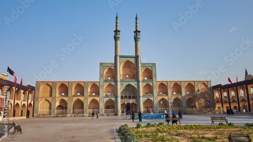 The walk along Amir Chakhmaq square to the building of Hosseinieh with multiple arched niches and tall minarets, decorated with tiled patterns, Yazd, Iran photo