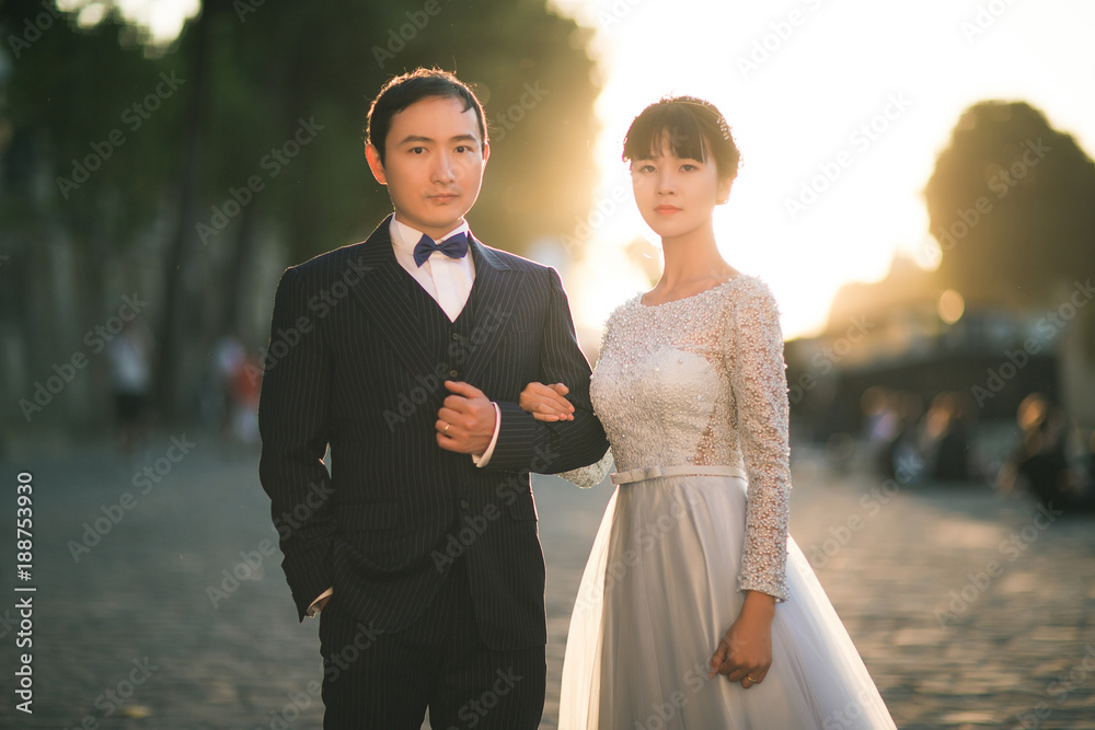 jeune couple de mariés asiatiques en contre-jour se tenant par le bras
