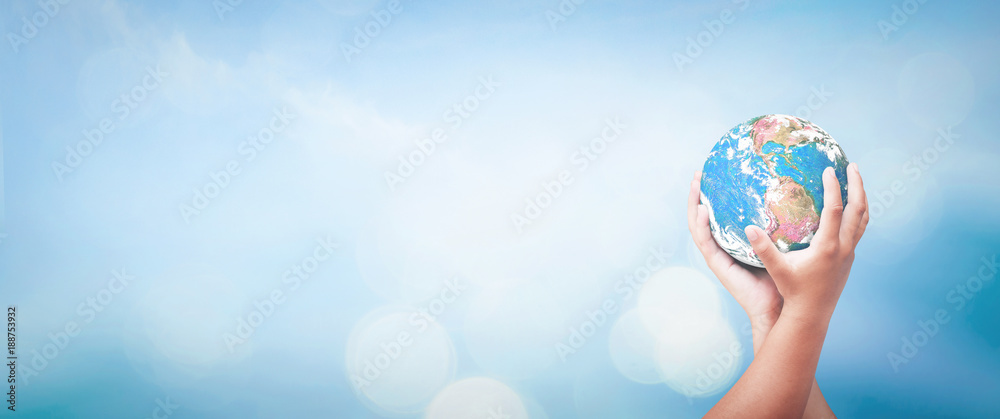 World environment day concept: Two human hands holding earth globe over blurred blue sky background. Elements of this image furnished by NASA - obrazy, fototapety, plakaty 