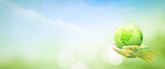 Double exposure of hands holding tree and green earth globe on nature sunrise background