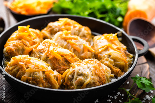 Cabbage rolls stewed with meat and vegetables in pan on dark wooden background photo