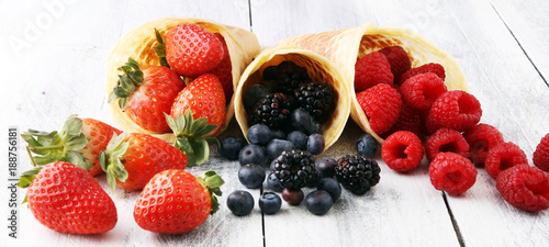 Fototapeta Naklejka Na Ścianę i Meble -  Berries in waffle cones - strawberry, blueberry and raspberry on wooden background