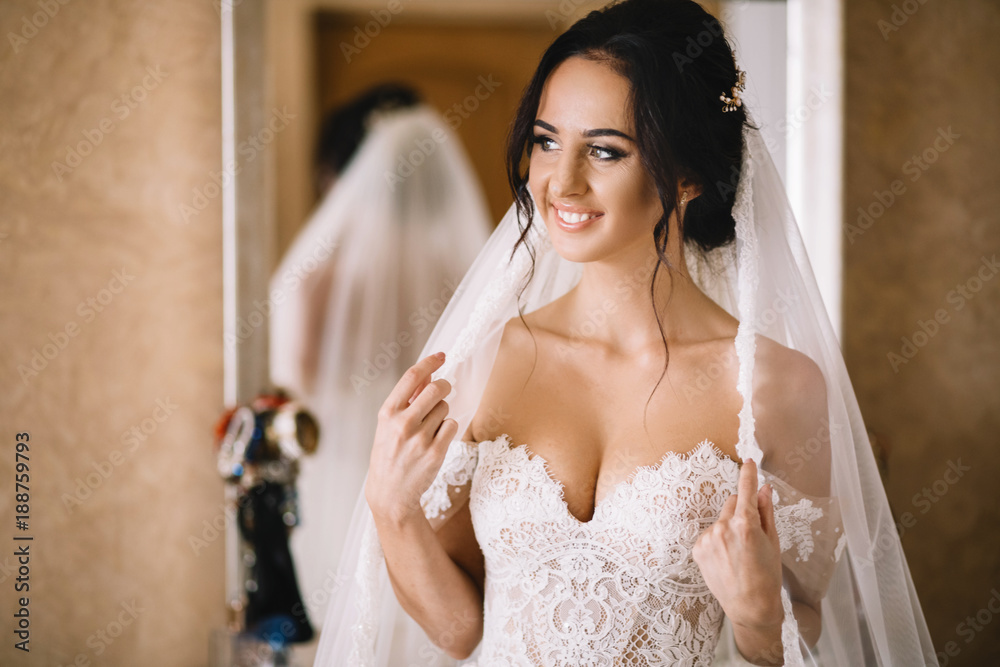 Fototapeta premium Bridesmaids whirl bride's veil while she smiles