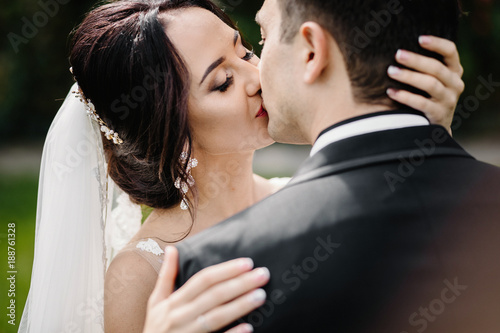 Confident elegant groom and beautiful shy bride holding hands ou © VAKSMANV