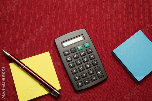 calculator two pads and pen on red background